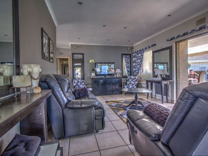 A spacious living room featuring tiled flooring, recessed downlighting, and a sliding glass door providing access to the outdoor patio area.