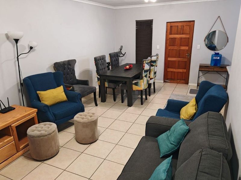Open plan living and dining area featuring neutral tiled flooring and a solid wood entrance door.