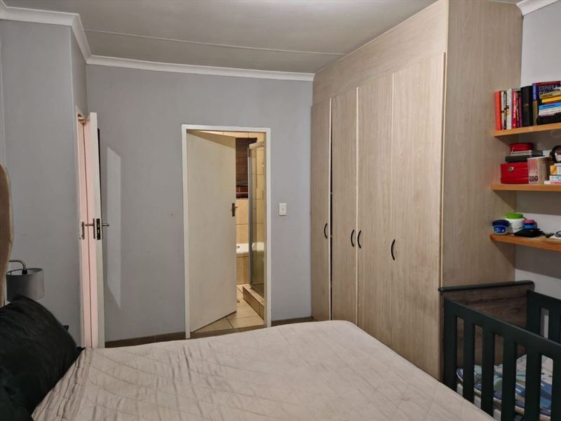 A bedroom featuring built-in wooden cupboards and direct access to an en-suite bathroom.