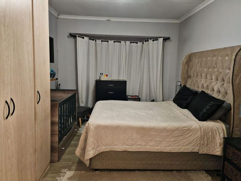 A functional bedroom featuring a built-in wardrobe and neutral wall finishes, providing a comfortable and practical sleeping space.