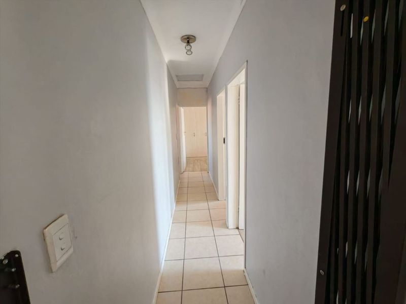 A clean, neutral hallway featuring tiled flooring and access to multiple internal rooms, providing a functional transition space within the townhouse.