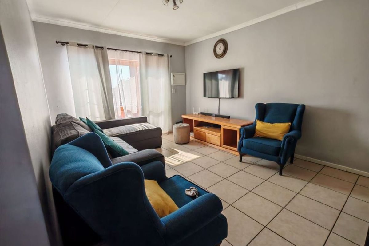 A living room featuring tiled flooring and a sliding glass door providing natural light.