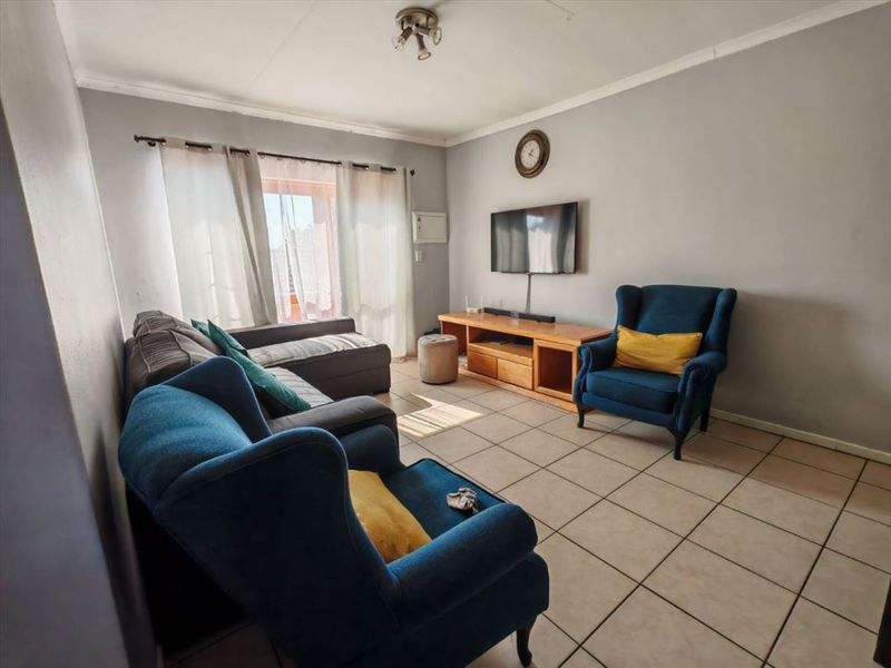 A living room featuring tiled flooring and a sliding glass door providing natural light.