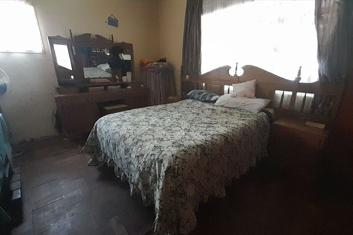 A bedroom featuring timber flooring and natural light, currently requiring cosmetic updates and wall repairs to enhance its overall appeal.