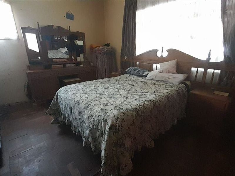 A bedroom featuring timber flooring and natural light, currently requiring cosmetic updates and wall repairs to enhance its overall appeal.