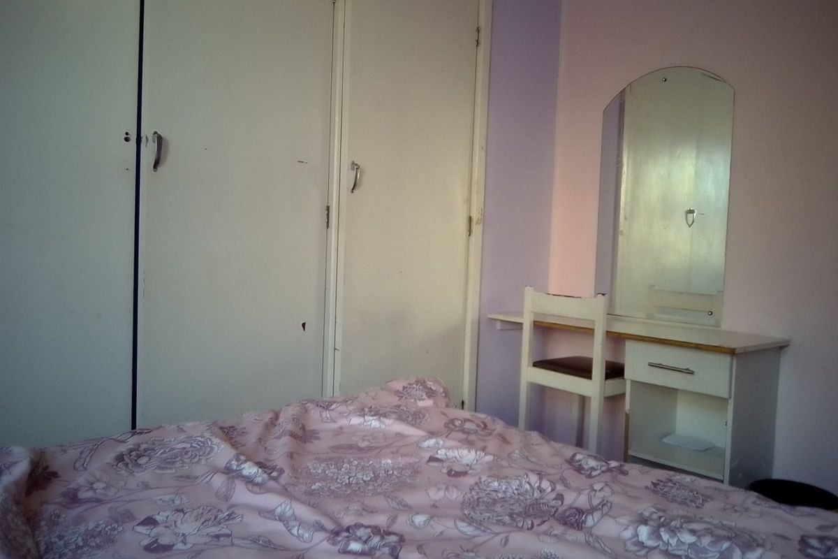 A bedroom featuring built-in cupboards and a vanity area, requiring cosmetic updates to improve the overall aesthetic and condition.