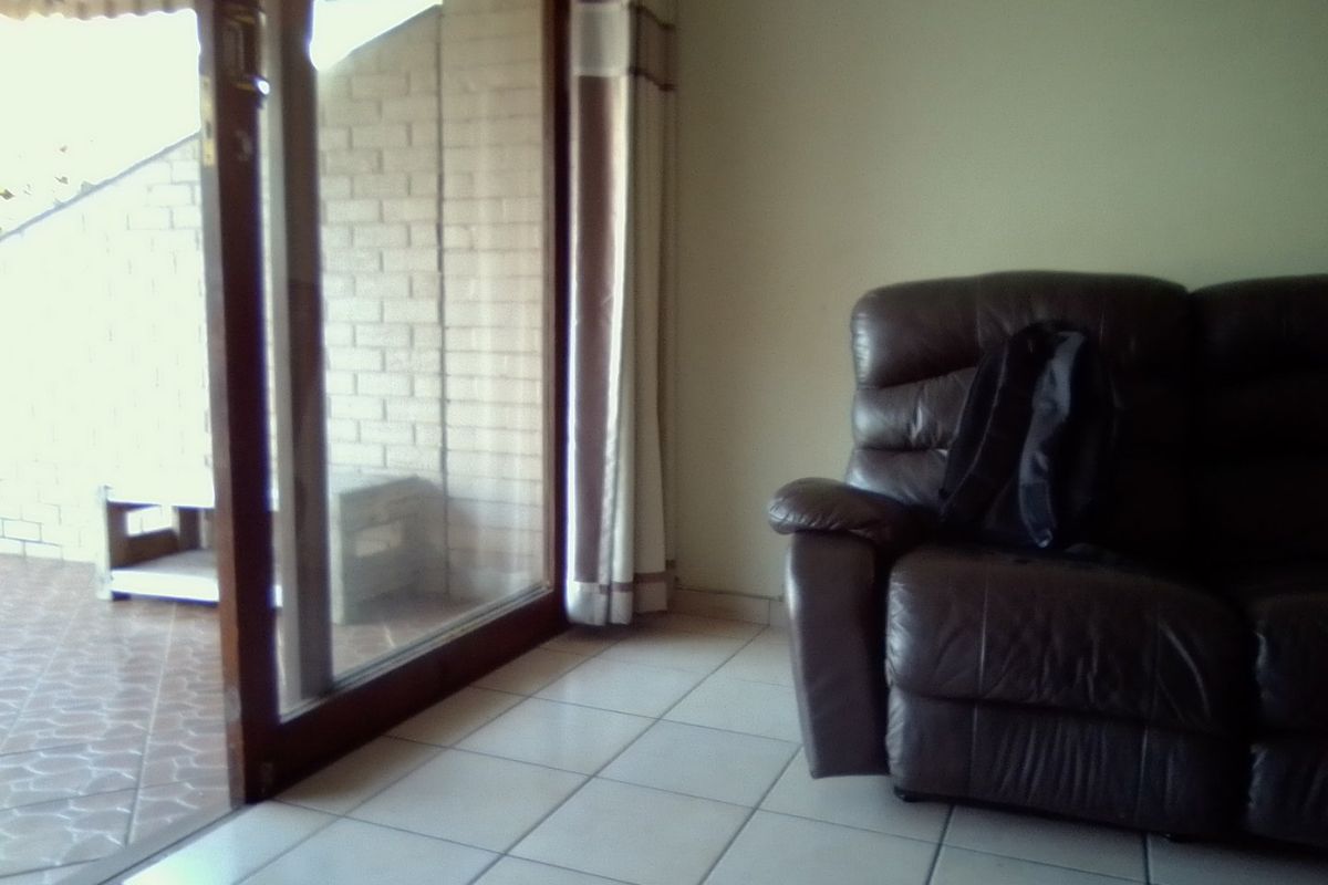 Living room area featuring tiled flooring and a large sliding glass door providing access to an outdoor patio space.