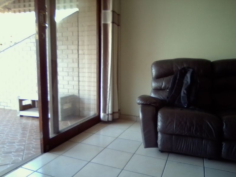 Living room area featuring tiled flooring and a large sliding glass door providing access to an outdoor patio space.