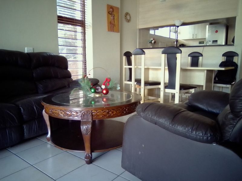 Open plan living and dining area featuring tiled flooring, venetian blinds, and a breakfast counter connecting to the kitchen space.