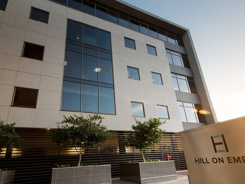 Modern commercial office building facade featuring large glass windows, stone cladding, and professional signage at the entrance.