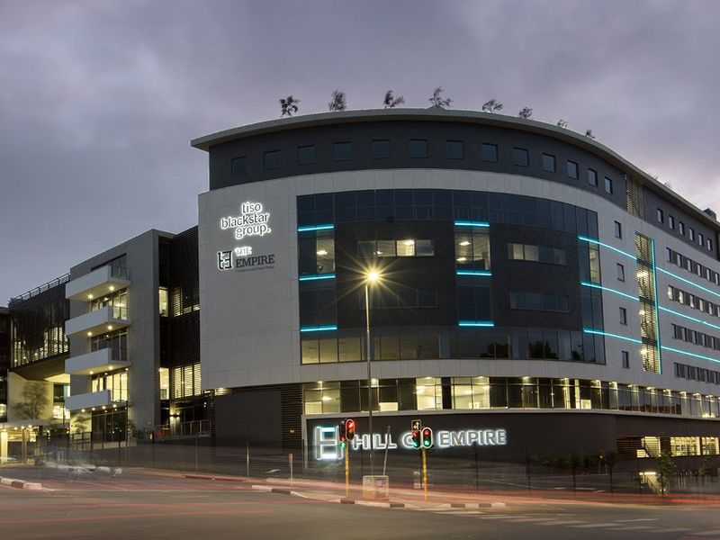 A modern multi-story commercial office building featuring contemporary facade design, integrated architectural lighting, and prominent signage at a prominent street corner location.