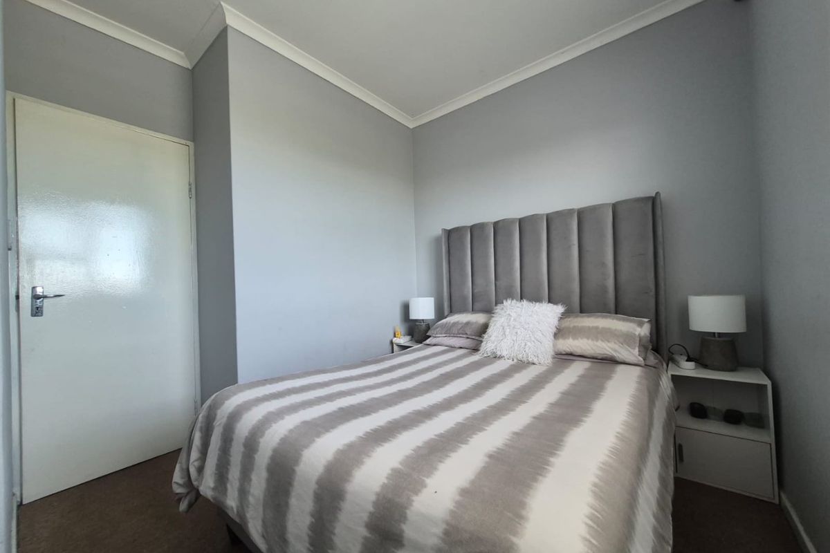 A well-maintained bedroom featuring neutral grey walls, cove cornicing, and a standard internal door.