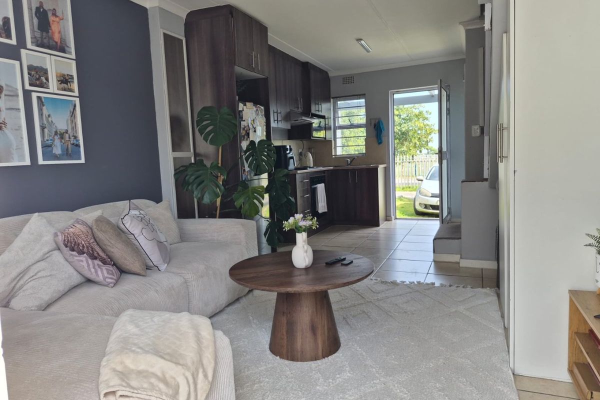 Open-plan living area featuring a modern kitchen with dark wood cabinetry, tiled floors, and direct access to the exterior.