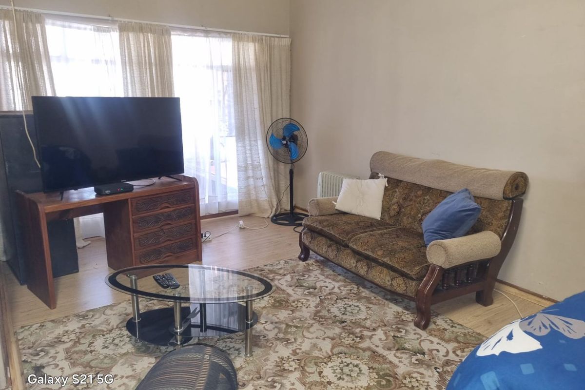 A living room featuring laminate flooring and a sliding glass door providing natural light.