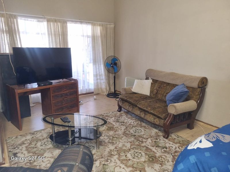 A living room featuring laminate flooring and a sliding glass door providing natural light.