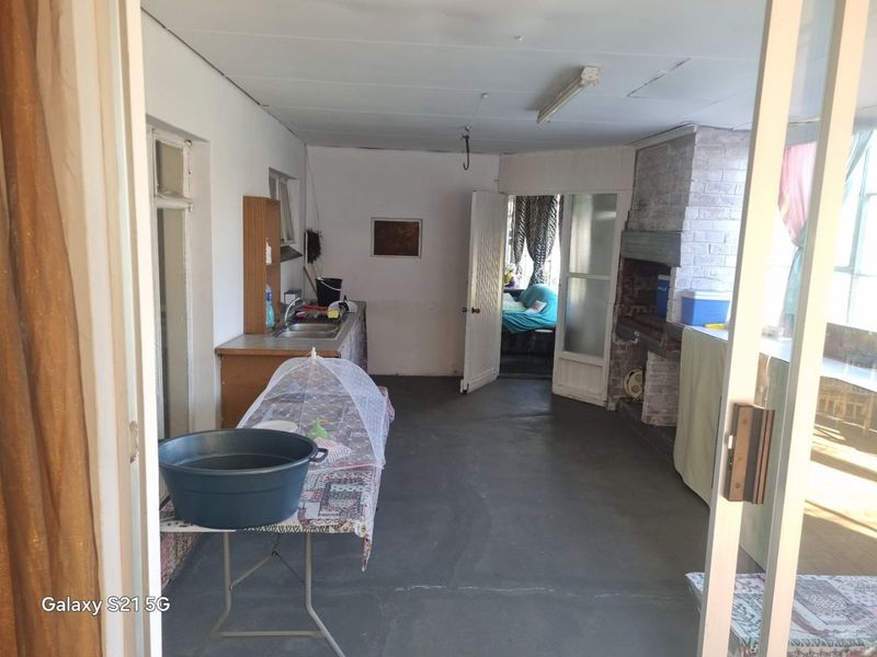 Covered patio area featuring a built-in brick braai and a basic kitchenette setup with sink and cabinetry.