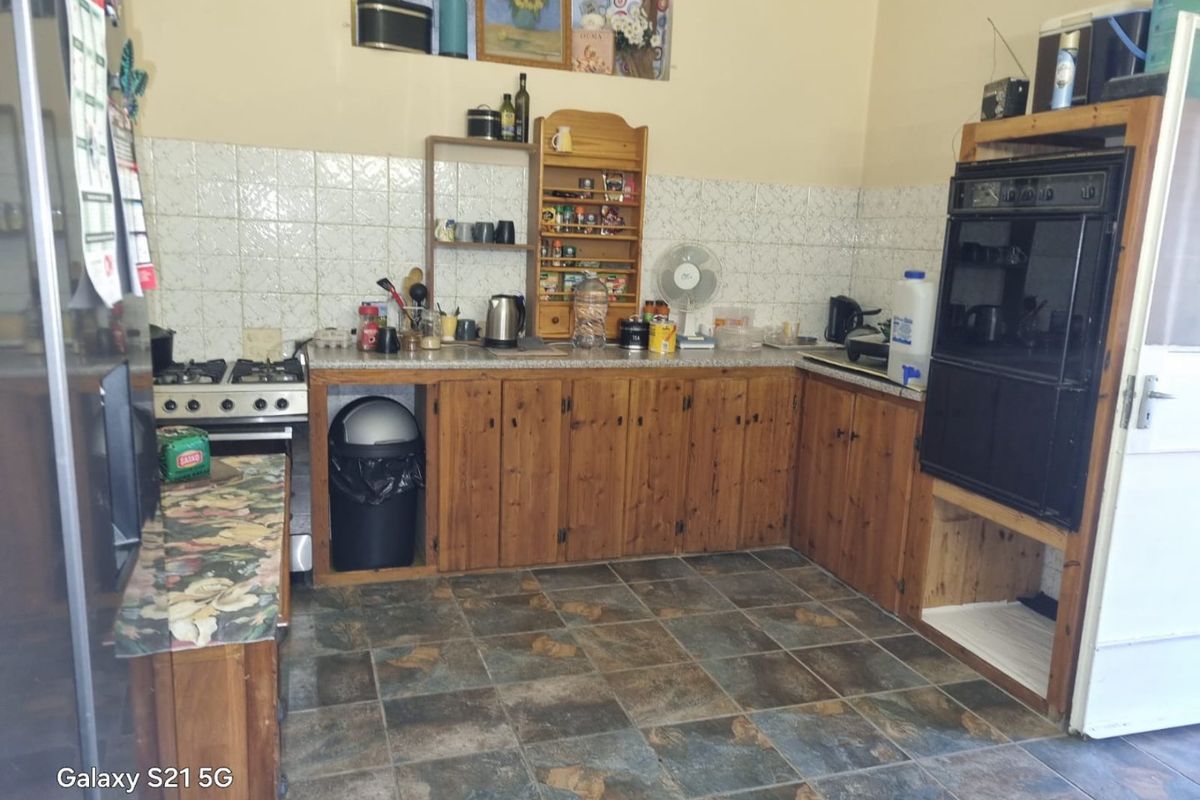 A dated kitchen featuring wooden cabinetry, a built-in oven, gas hob, and tiled splashback, offering potential for a modern renovation.