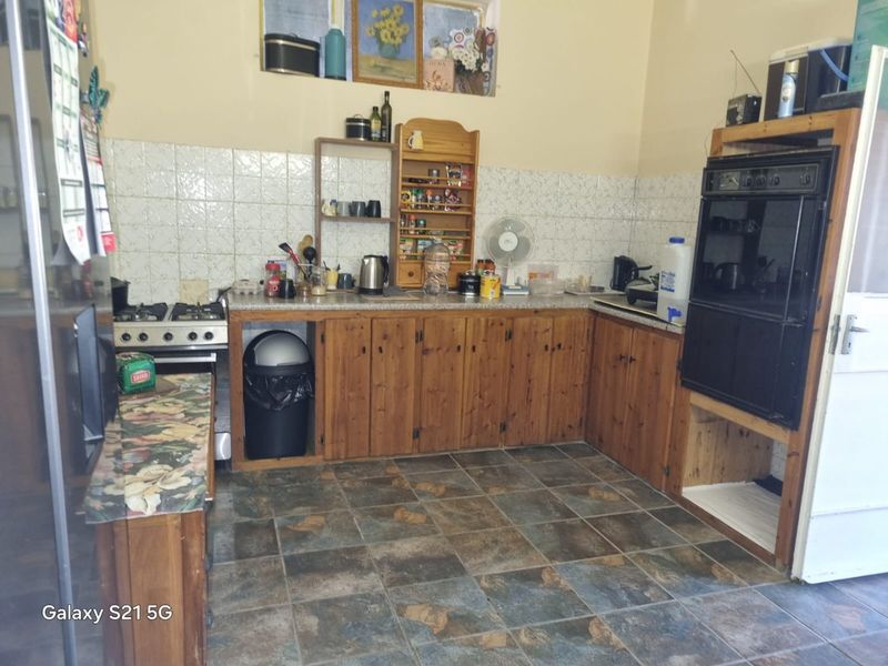 A dated kitchen featuring wooden cabinetry, a built-in oven, gas hob, and tiled splashback, offering potential for a modern renovation.