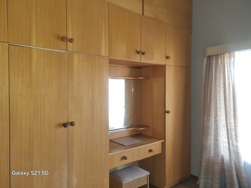 Bedroom featuring extensive floor-to-ceiling wooden built-in cupboards with an integrated vanity and mirror.