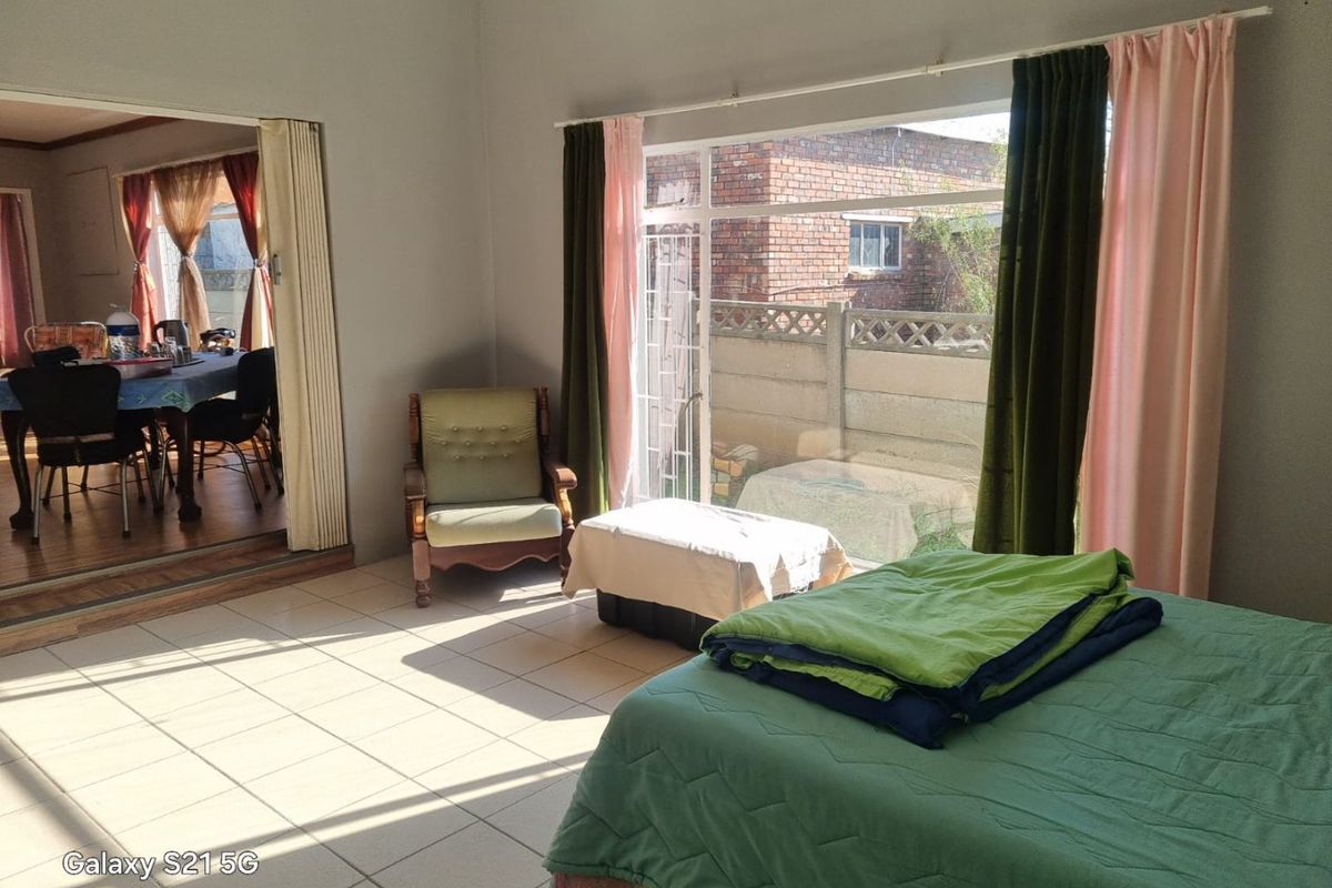 Spacious bedroom featuring tiled flooring and a large sliding glass door with access to the exterior, providing ample natural light.