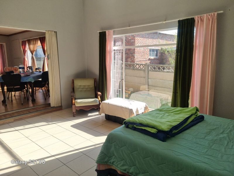 Spacious bedroom featuring tiled flooring and a large sliding glass door with access to the exterior, providing ample natural light.