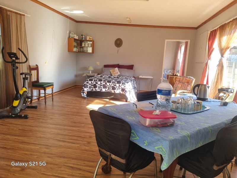 A spacious bedroom featuring laminate flooring and timber crown molding, offering a versatile layout with natural light.