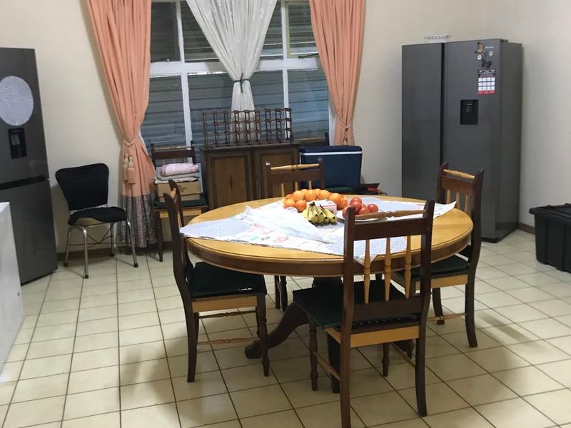 A functional dining area featuring tiled flooring and a large window, providing a bright and practical space for family meals.