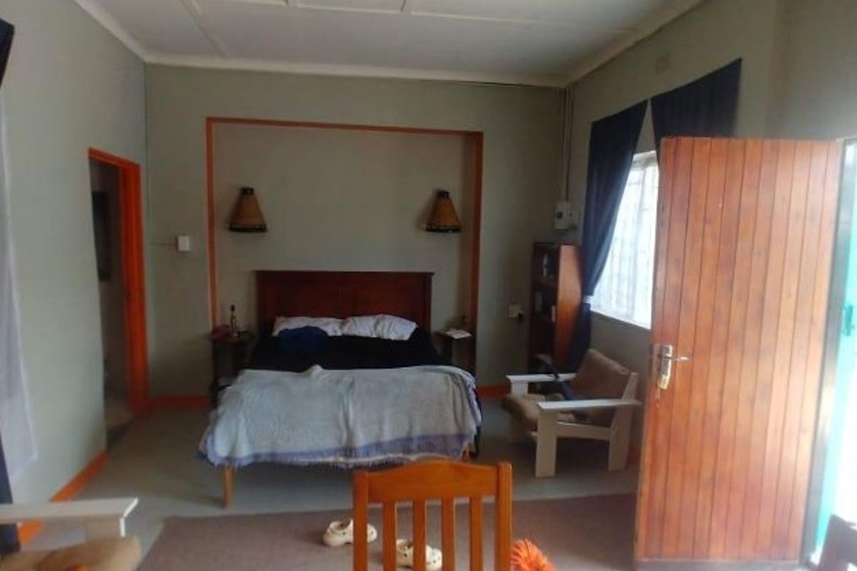 A bedroom featuring a recessed wall niche with integrated lighting, a timber door, and natural light from the window.