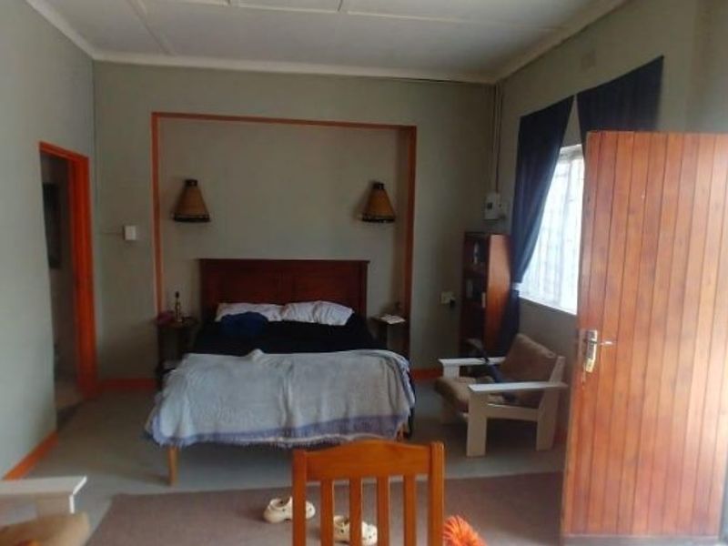 A bedroom featuring a recessed wall niche with integrated lighting, a timber door, and natural light from the window.