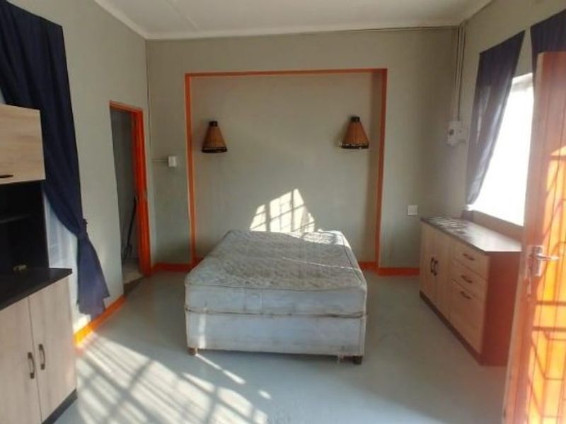 A bedroom featuring built-in wall sconces and a security gate on the window, with painted door frames and neutral wall tones.