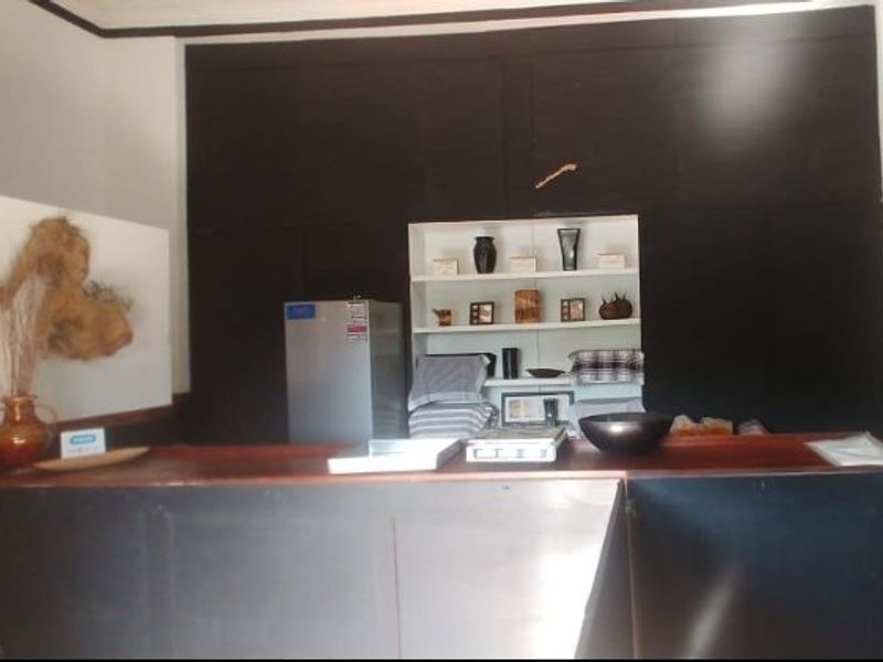 A commercial bar area featuring a dark wood-finish counter and integrated shelving for display or storage.