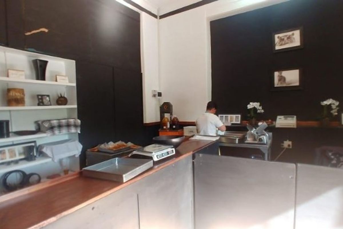 Commercial kitchen service area featuring a wooden counter, stainless steel prep surfaces, and built-in wall shelving.