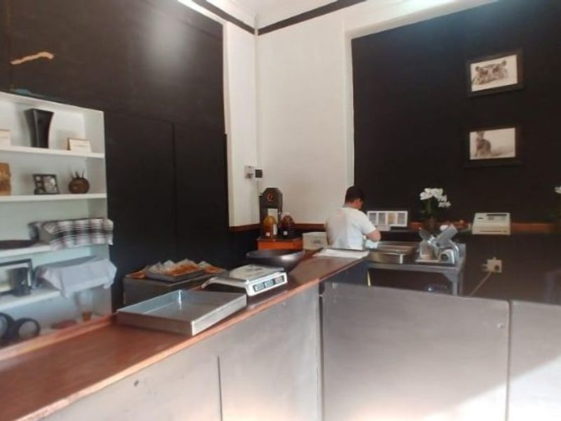 Commercial kitchen service area featuring a wooden counter, stainless steel prep surfaces, and built-in wall shelving.