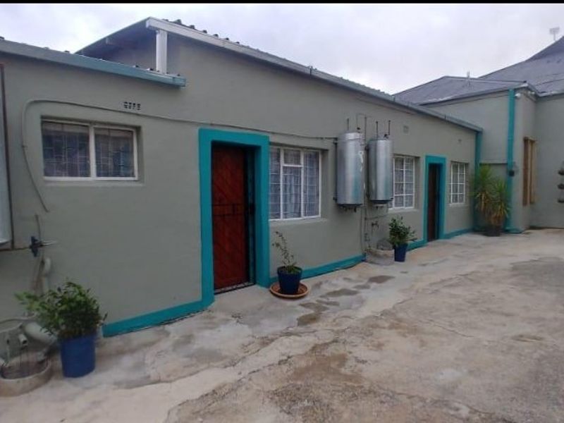 Rear exterior view of a commercial property featuring concrete paving, multiple external geysers, and security-fitted doorways.