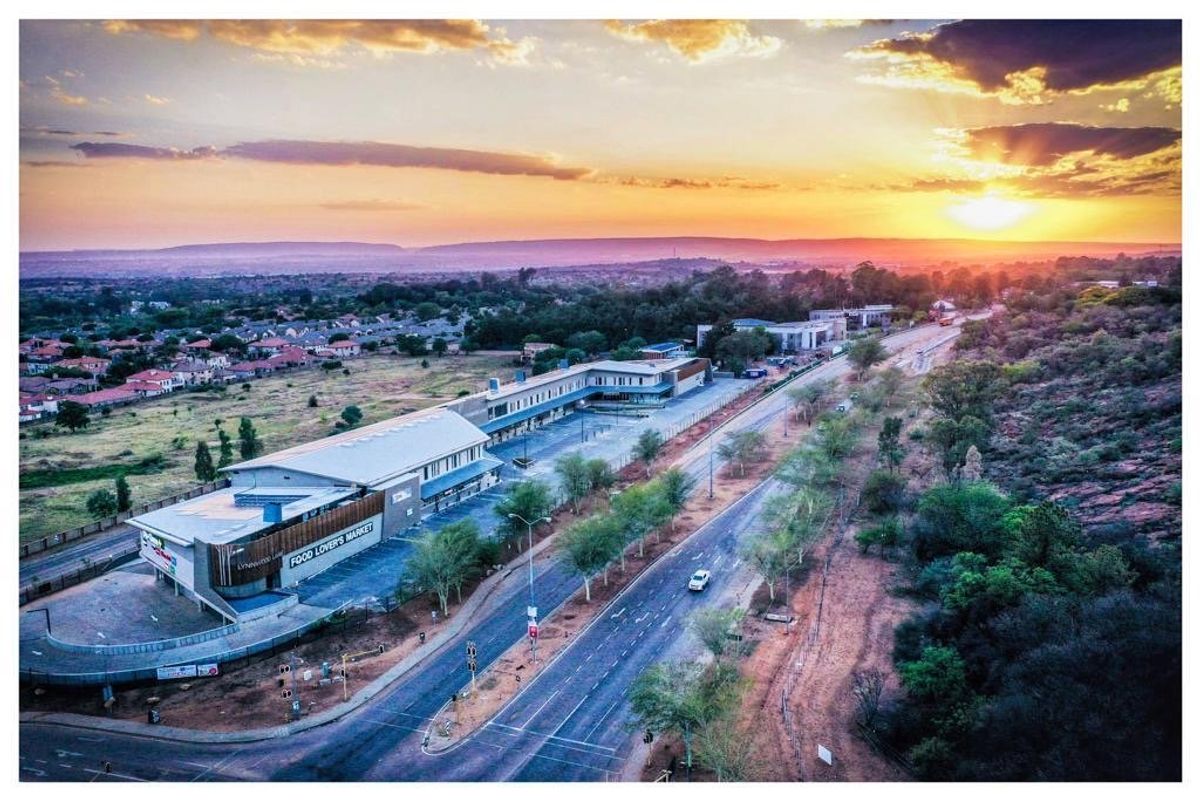 Aerial view of a commercial retail complex featuring a large parking area and road access at sunset.