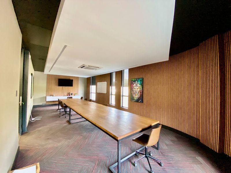Modern office boardroom featuring timber slat wall paneling, recessed ceiling with integrated air conditioning, and large windows providing natural light.