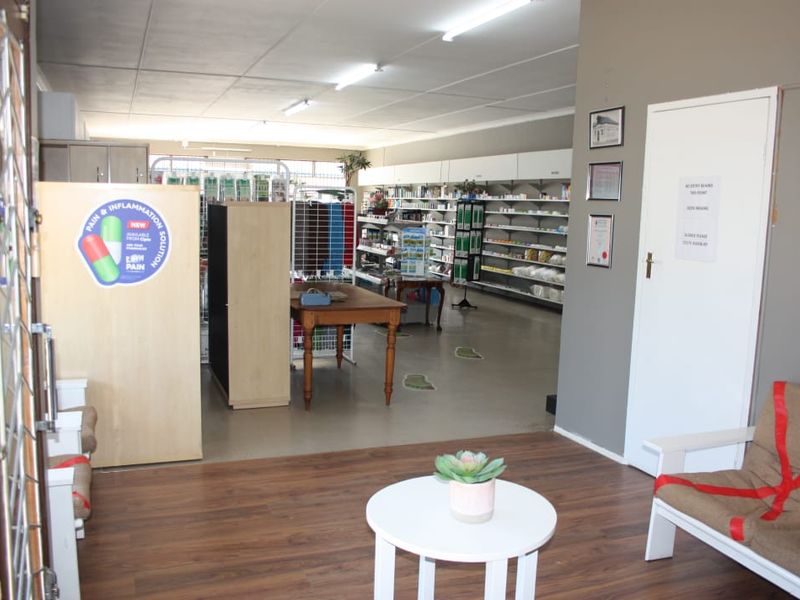 Commercial retail space featuring open-plan layout with built-in shelving units, fluorescent lighting, and a combination of laminate and vinyl flooring.