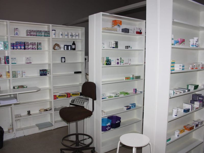 Commercial utility space featuring multiple rows of white built-in shelving units for organized storage.