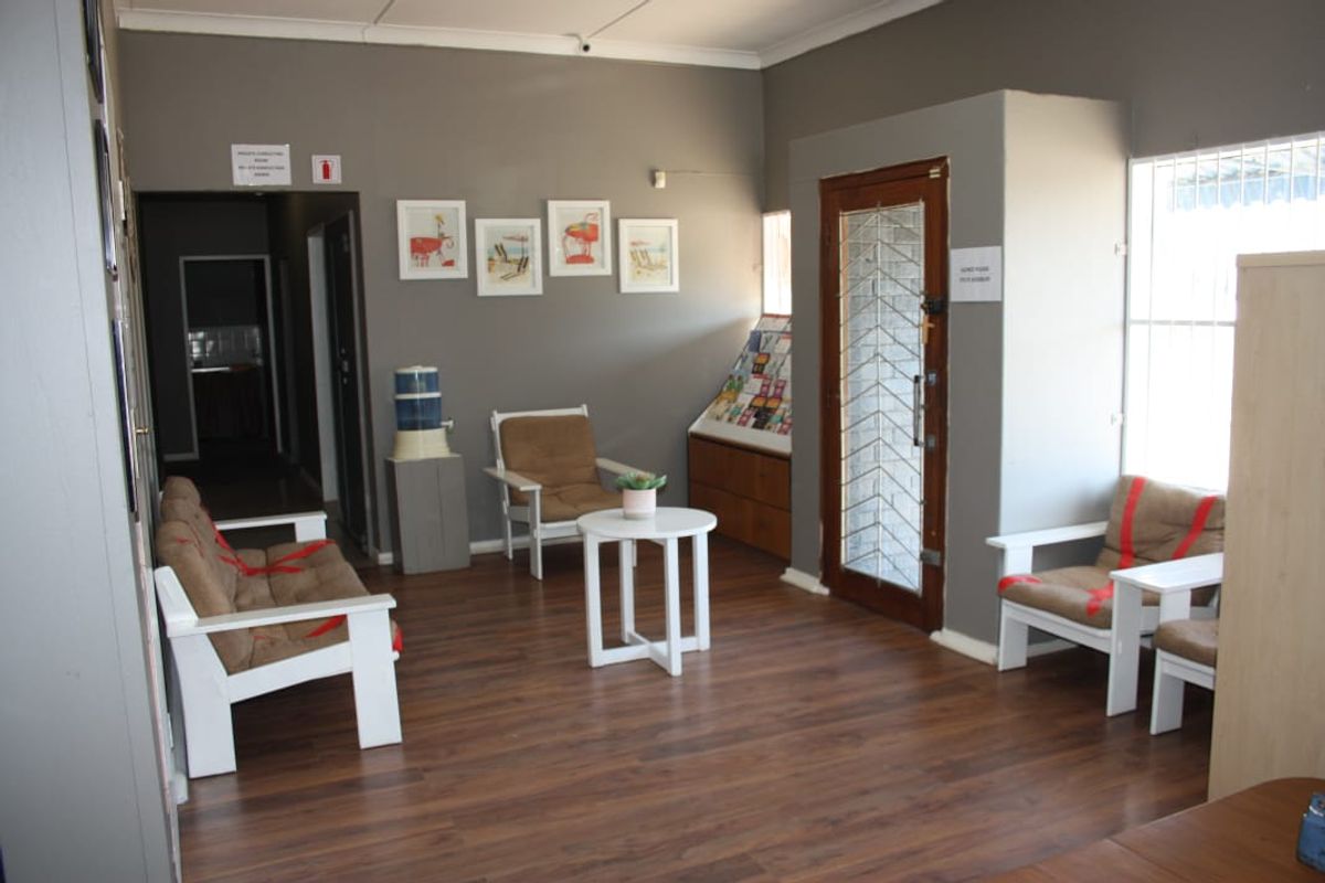 A commercial reception or entry area featuring laminate flooring, security-fitted doors and windows, and built-in display shelving.