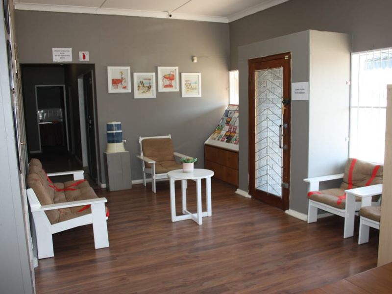 A commercial reception or entry area featuring laminate flooring, security-fitted doors and windows, and built-in display shelving.