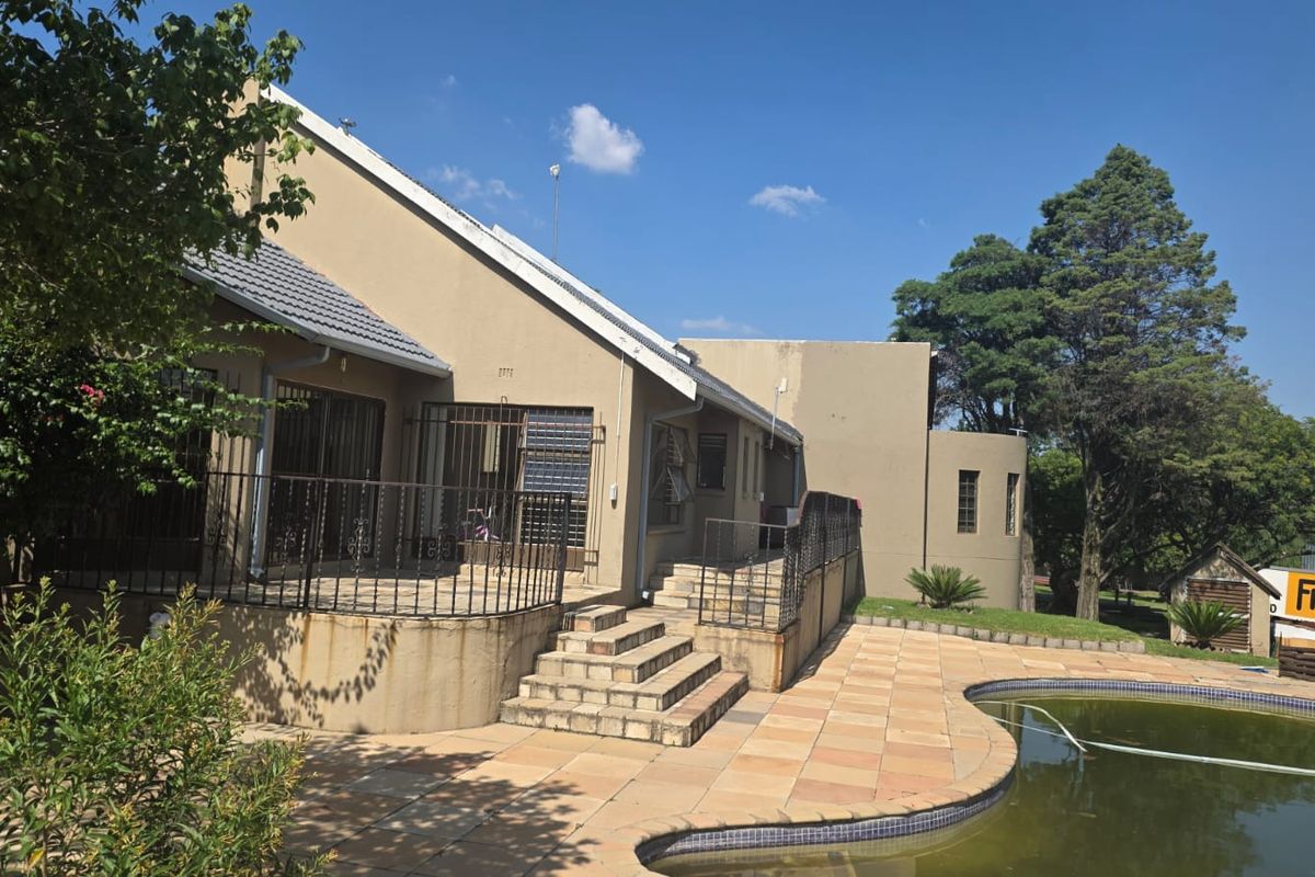 Rear exterior view featuring a paved patio area, metal security railings, concrete stairs, and a swimming pool requiring maintenance.