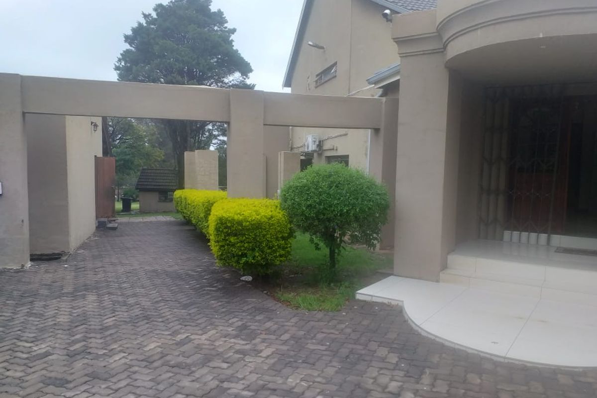 Front exterior view of the property featuring a paved driveway, covered entrance area with tiled steps, and established garden hedging.