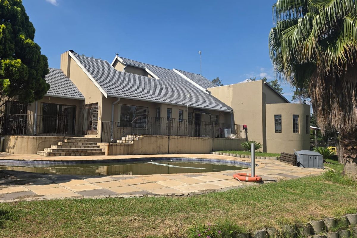 Rear view of the property featuring a swimming pool, paved patio area, and access stairs leading to the main house structure.