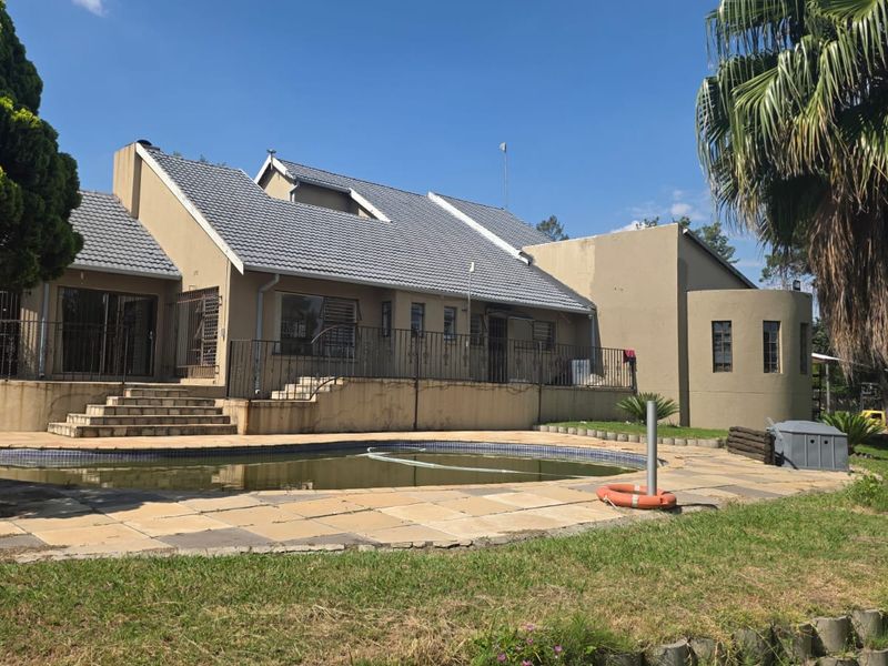 Rear view of the property featuring a swimming pool, paved patio area, and access stairs leading to the main house structure.