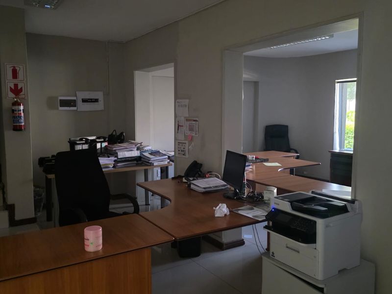 A functional office space featuring tiled flooring, built-in electrical distribution board, and fire safety equipment, suitable for a professional work environment.