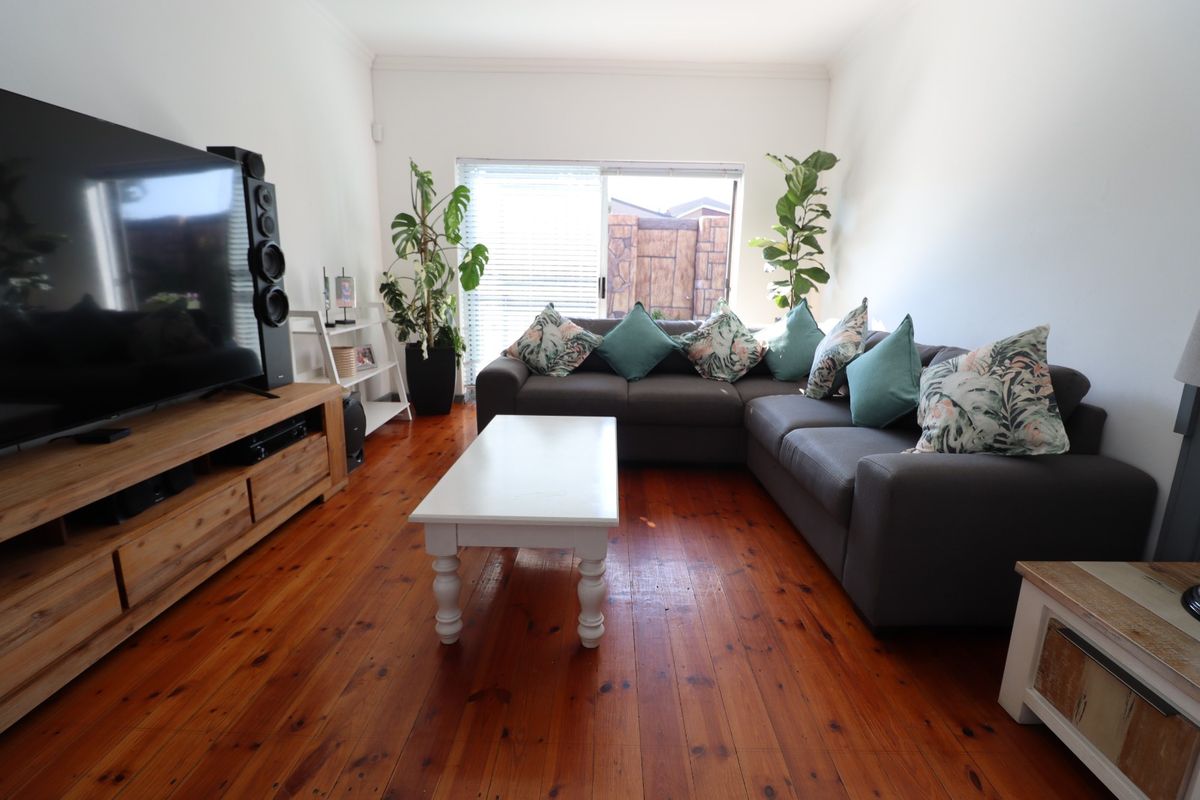 A comfortable living room featuring warm timber flooring and a sliding glass door that provides natural light and access to the outdoor area.