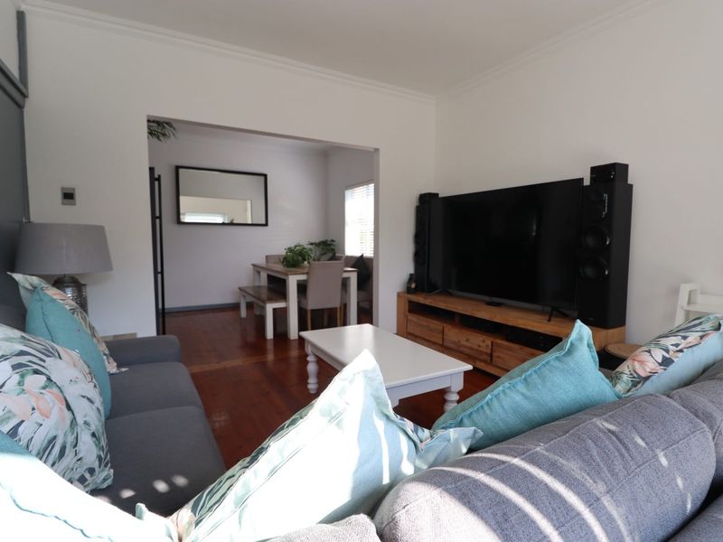 An open-plan living and dining area featuring polished hardwood flooring and classic cove cornicing, creating a bright and connected living space.