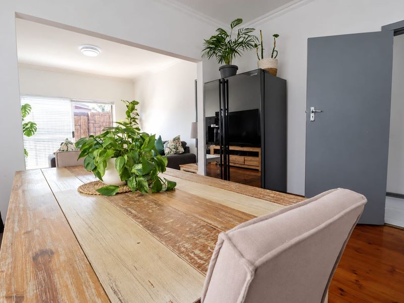 An open-plan living and dining area featuring warm hardwood flooring, crown molding, and a seamless transition between the dining space and the adjacent lounge.