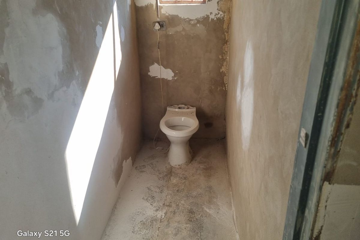 A small, unfinished bathroom space featuring a toilet, requiring significant renovation and finishing of walls and flooring.