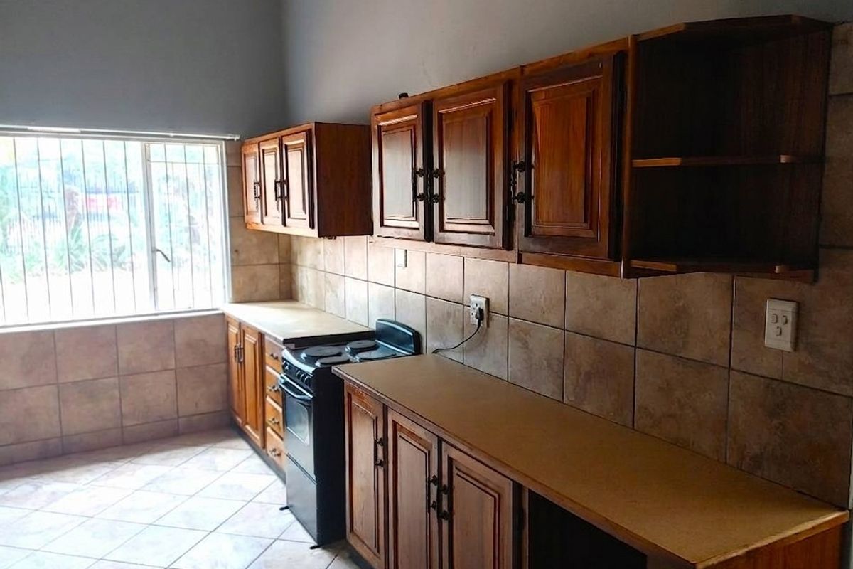 A functional kitchen featuring wooden cabinetry, tiled backsplash, and a freestanding stove, offering a practical layout with potential for modern updates.